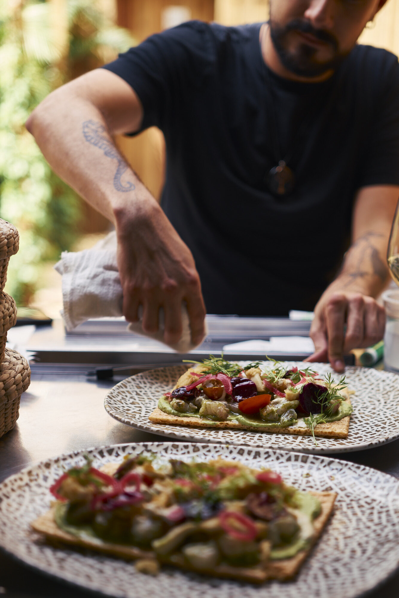 Cocinero emplatando dos tostadas de vegetales